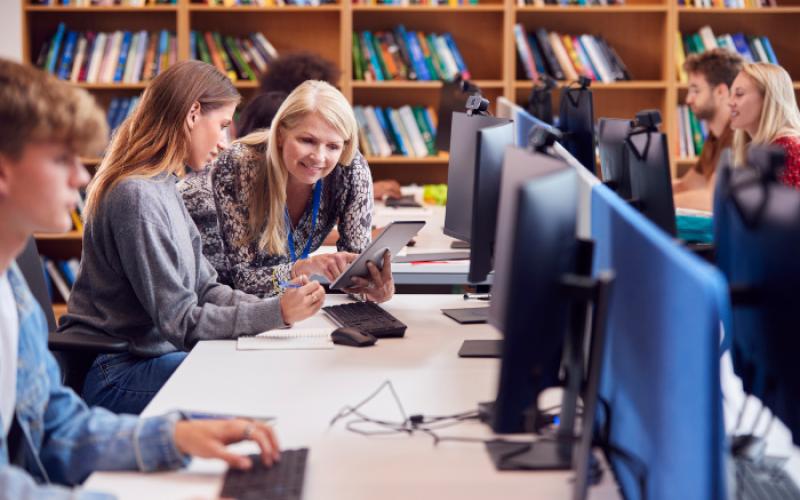 Teacher and students using computers in library