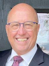 Head shot of David Ivey smiling in a suit and tie