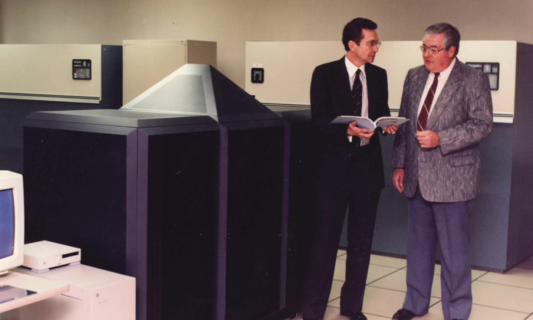 Two executives in suits standing next to nCUBE supercomputer in data center