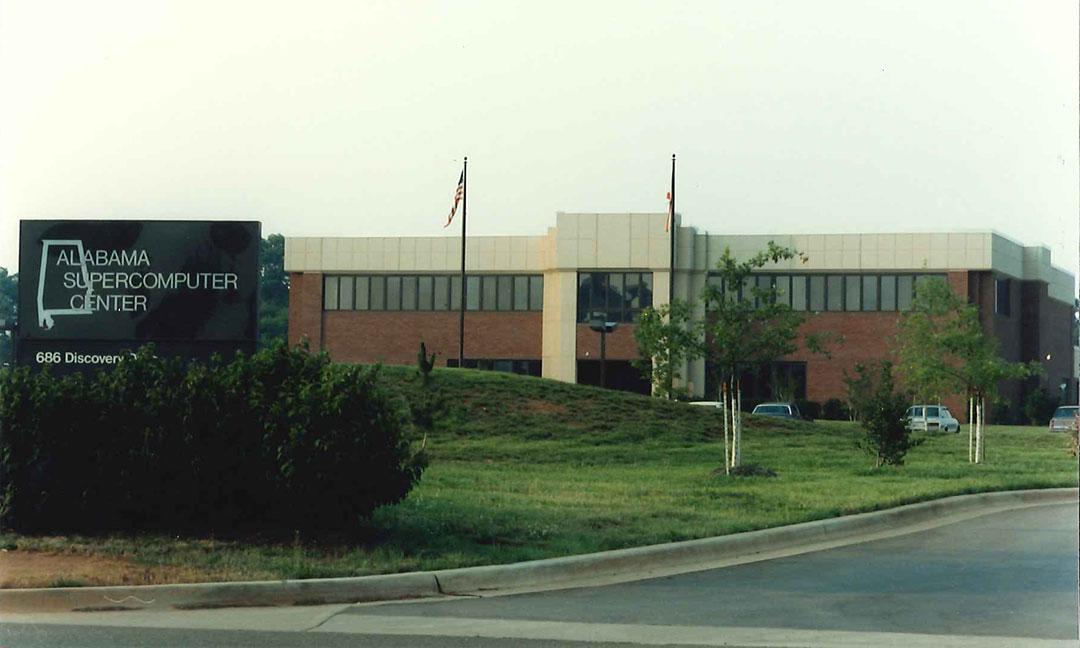 Front view of Alabama Supercomputer Center brick and stucko building with the Alabama Supercomputer Center sign in the foreground