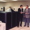 Two executives in suits standing next to nCUBE supercomputer in data center